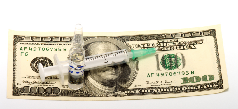a syringe and vial sitting on top of a US $100 bill