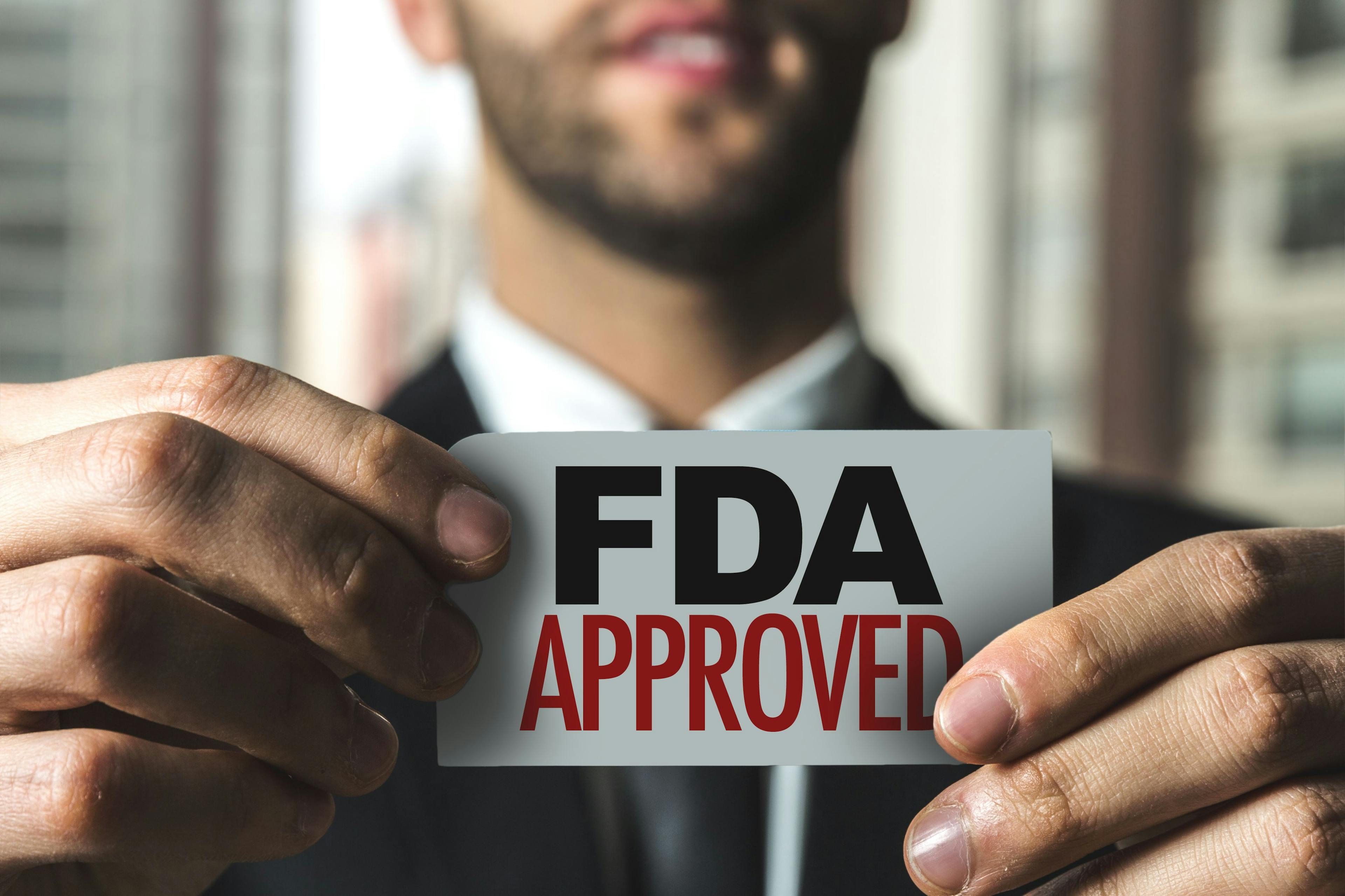 Guy holding paper "FDA Approved" | Image credit: gustavofrazao - stock.adobe.com