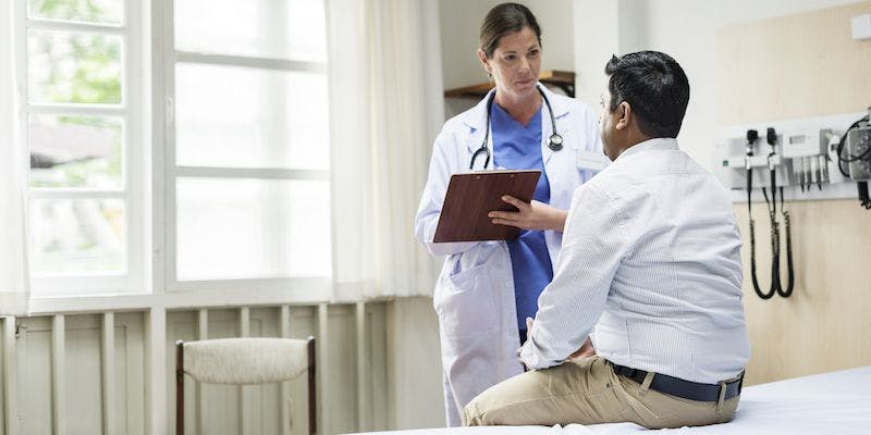 doctor taking notes while talking to a patient