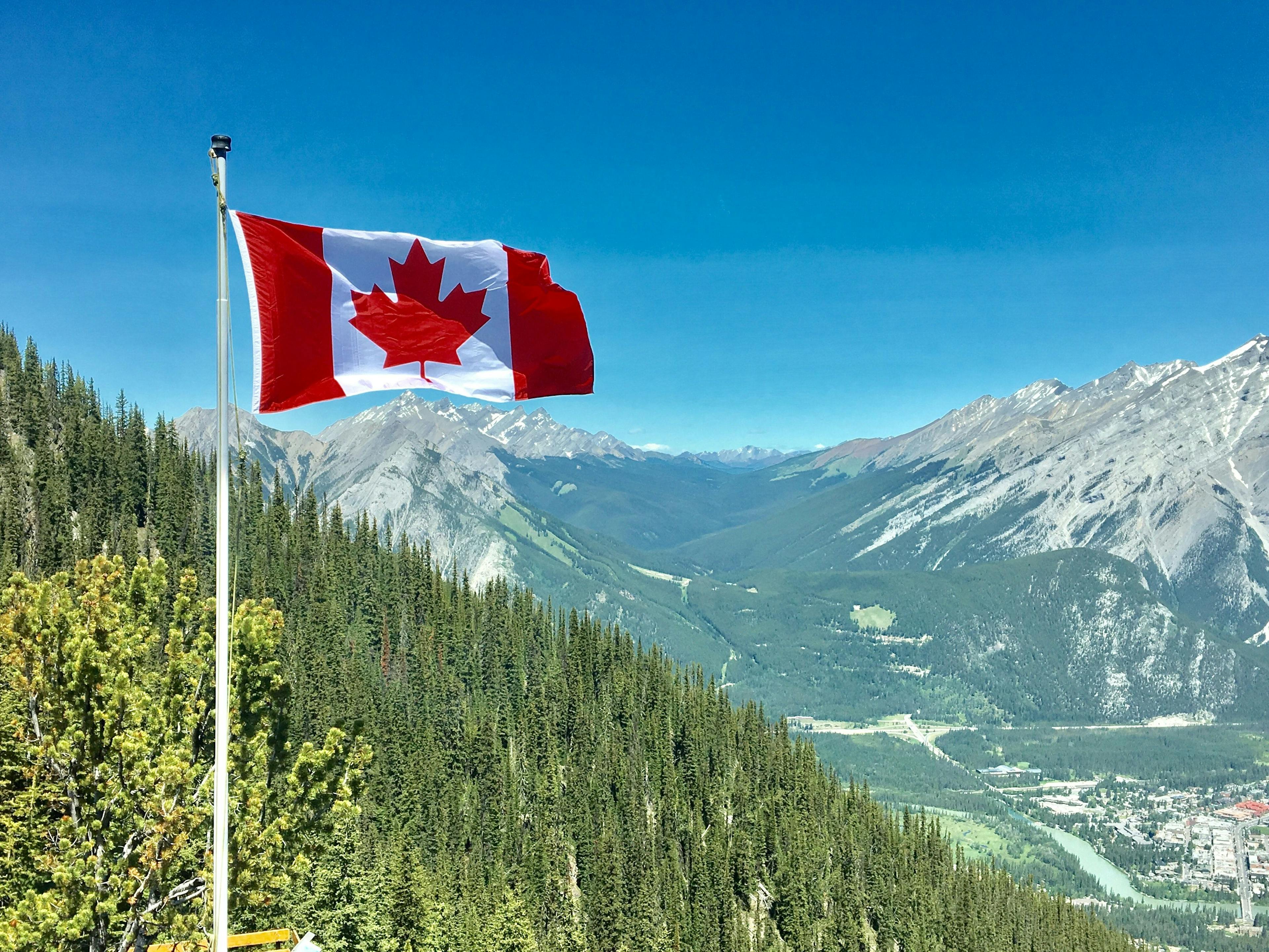 canadian flag over looking mountain range