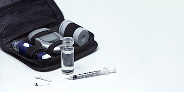 insulin vial next to needle and glucose monitor