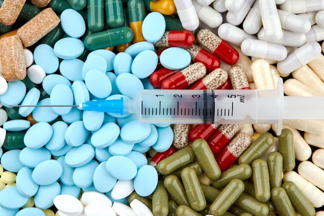 syringe over pile of pills