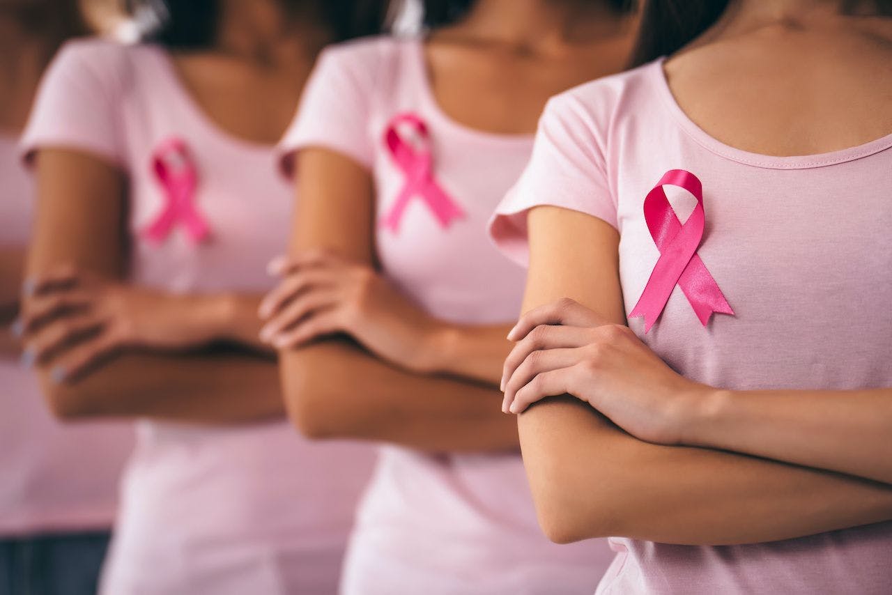 woman with breast cancer ribbon standing in a line with crossed arms