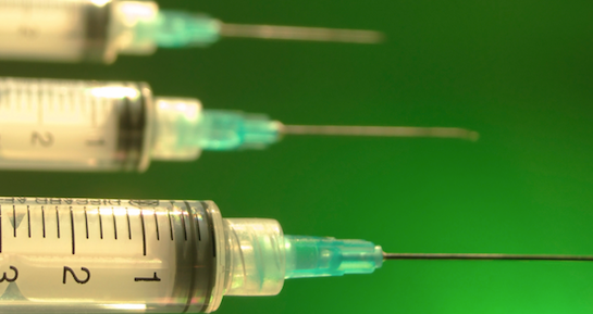 syringes lined up next to each other over a green background