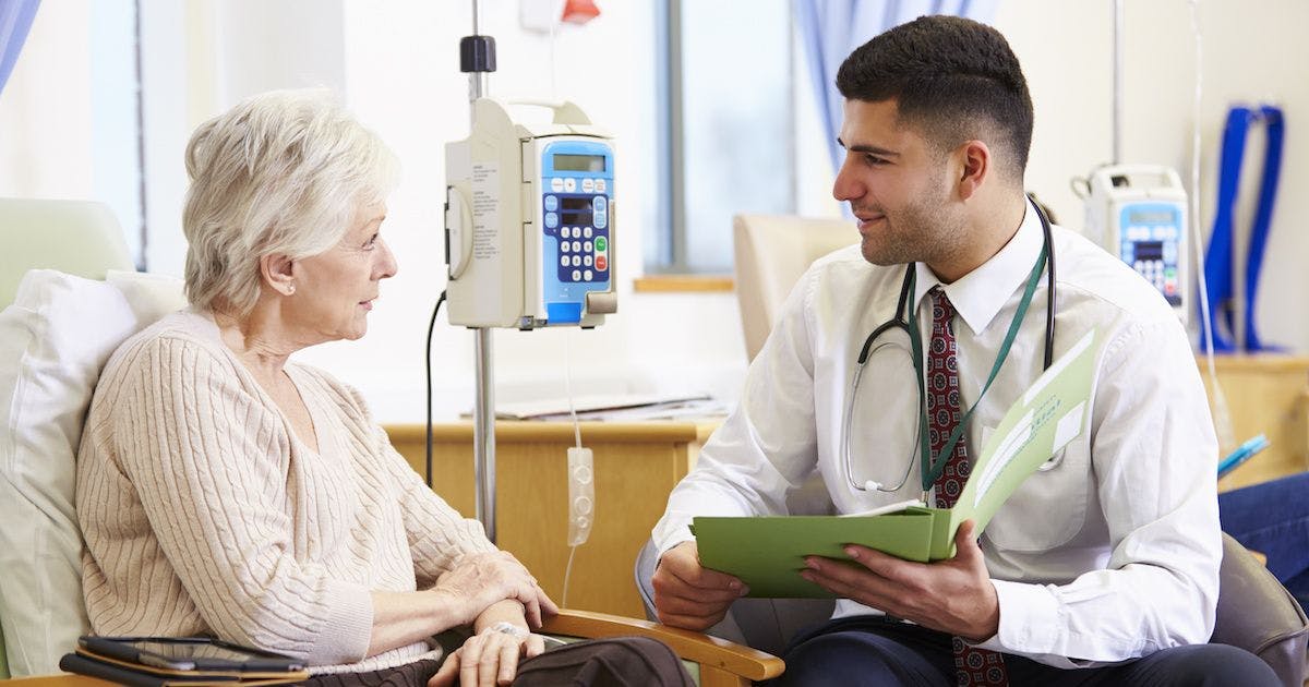 elderly cancer patient talking to doctor while receiving chemotherapy